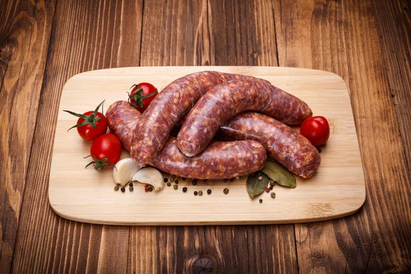 Saucisses épaisses de porc cru sur planche à découper — Photo