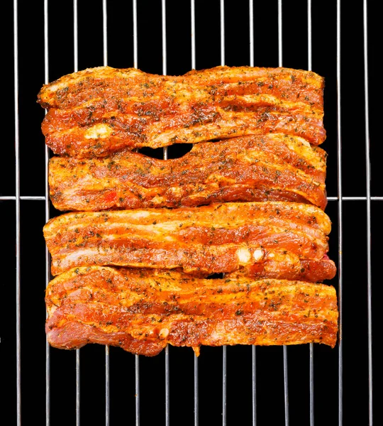 Marinated belly slices on barbecue grid — Stock Photo, Image