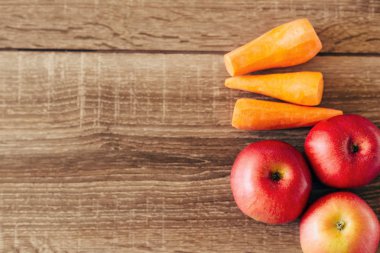 Kırmızı elma ve ahşap masa üzerinde sarı havuç