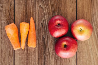 Kırmızı elma ve ahşap masa üzerinde sarı havuç