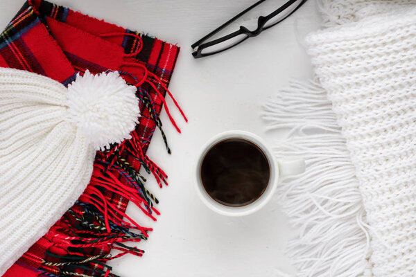Handmade knitted wool scarf and cap. Winter clothes. Hot coffee cup on wooden background. Concept cozy atmosphere with a of in . Top view