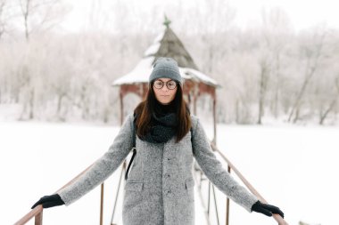 Kışın köprüdeki gri paltolu kız