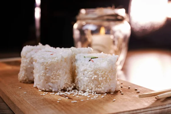 Japanese food, sushi roll with crab, sesame seeds, cucumber, cheese, on a wooden board — Stock Photo, Image