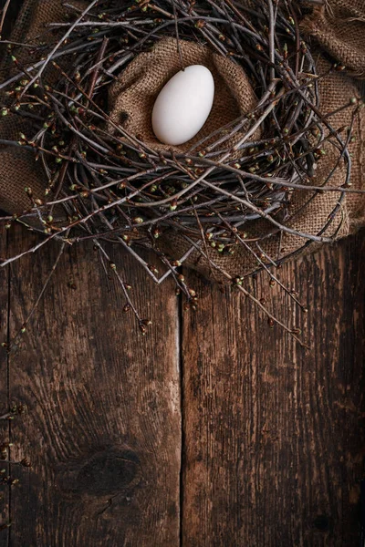 Un huevo grande en el nido con ramas de primavera, sobre una vieja mesa de madera — Foto de Stock