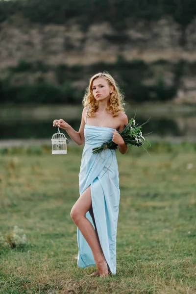 Menina com flores e uma gaiola para um pássaro — Fotografia de Stock