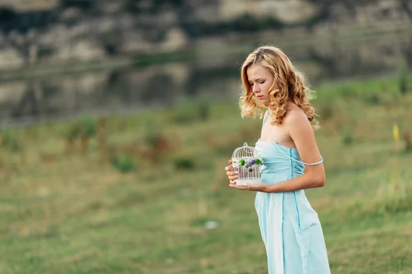 Licht krullend meisje in een blauwe jurk, fotosessie in het voorjaar op de natuur — Stockfoto