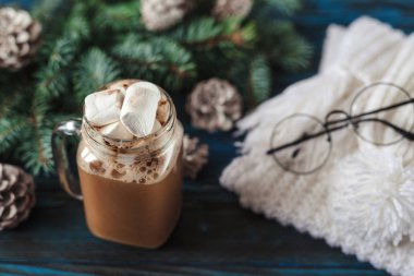 Yeni yıl kapuçino marshmallow, eski mavi ahşap masa, Dekorasyon, çam kozalakları ile bir dal için için atkı örgü beyaz ile