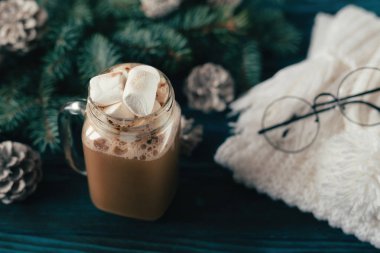 Yeni yıl kapuçino marshmallow, eski mavi ahşap masa, Dekorasyon, çam kozalakları ile bir dal için için atkı örgü beyaz ile