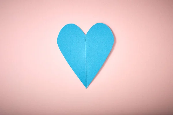 Blue paper heart on pink paper