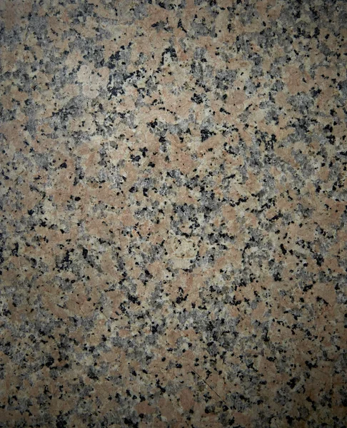 Granite Blacksmith. Natural stone texture with pink-red color with a lot of black inclusions. The surface of the building material for finishing floors and walls, fireplaces and staircases