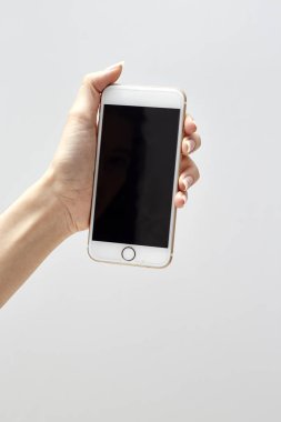 Beyaz arka planda, modern bir akıllı telefon tutarak ve figer, kendi web sayfası veya mesaj koymak için boş ekran ile işaret kızın elini cep telefonu üzerinde tipik bir kadın portre çekim izole.
