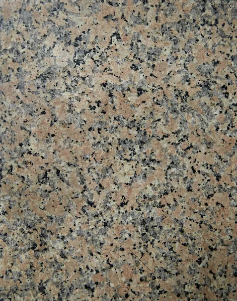 Granite Blacksmith. Natural stone texture with pink-red color with a lot of black inclusions. The surface of the building material for finishing floors and walls, fireplaces and staircases