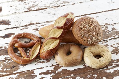 Kepekli ekmek, baget ve simit Beyaz ahşap zemin üzerinde