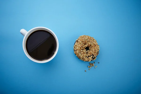 cup of black coffee and donut on blue background