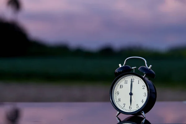 Orologio a campana nero su tavolo in legno in giardino — Foto Stock