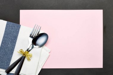 Gümüş kaşık ve pembe gri arka plan üzerinde beyaz peçete