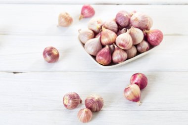 Ahşap beyaz masa arka plan üzerinde seramik kase taze sarımsak