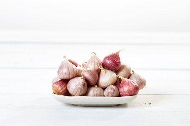 Ahşap beyaz masa arka plan üzerinde seramik kase taze sarımsak