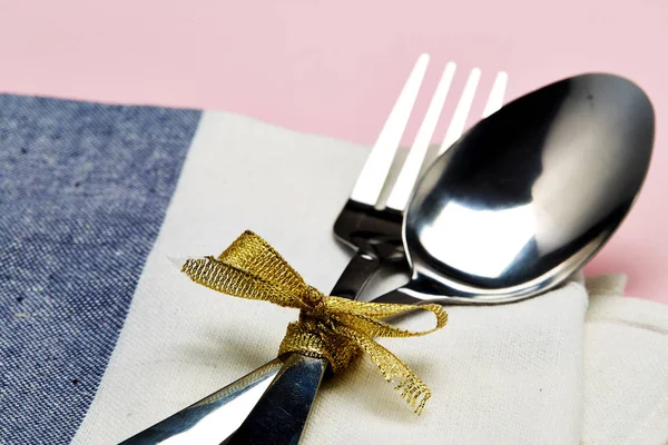Set table with silver spoon and white napkin on pink with gray background