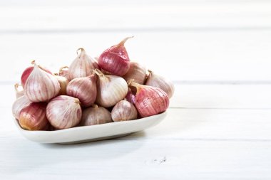 Ahşap beyaz masa arka plan üzerinde seramik kase taze sarımsak