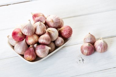 Ahşap beyaz masa arka plan üzerinde seramik kase taze sarımsak