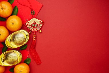 Şans ya da Çin düğüm ve Çin altın İngotlar ve geleneksel Çin düğüm (nimet yabancı metin anlamına gelir) ve kırmızı zarf ve dekorasyon kırmızı Kağıt arka plan üzerinde taze portakal ile Çin paraları