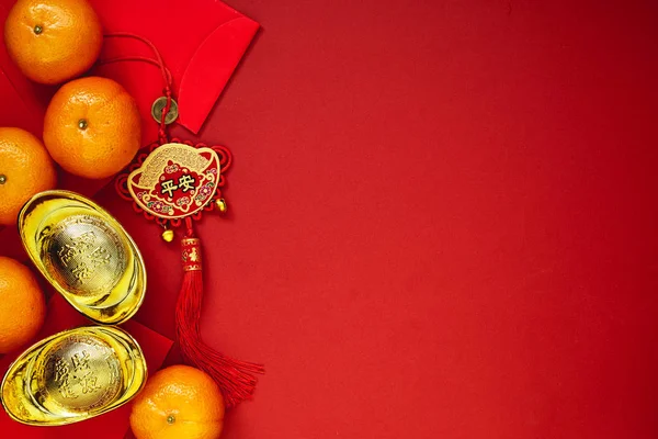 Chinese coins of luck or chinese knot and Chinese gold ingots and Traditional chinese knot  (Foreign text means blessing) and Red envelopes and decoration with Fresh oranges on Red Paper background