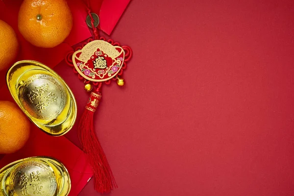 Chinese coins of luck or chinese knot and Chinese gold ingots and Traditional chinese knot  (Foreign text means blessing) and Red envelopes and decoration with Fresh oranges on Red Paper background
