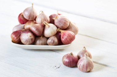 Ahşap beyaz masa arka plan üzerinde seramik kase taze sarımsak