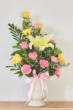 Buket sarı Lily Rose sarı çiçek ve bir vazo içinde pembe karanfil yaprakları