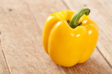 Ahşap masa üzerinde tek turuncu sarı dolmalık biber