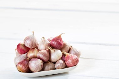 Ahşap beyaz masa arka plan üzerinde seramik kase taze sarımsak