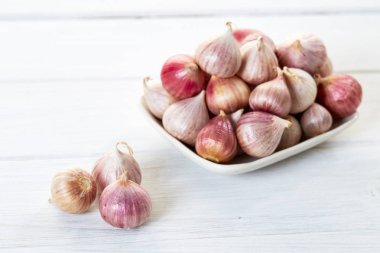 Ahşap beyaz masa arka plan üzerinde seramik kase taze sarımsak