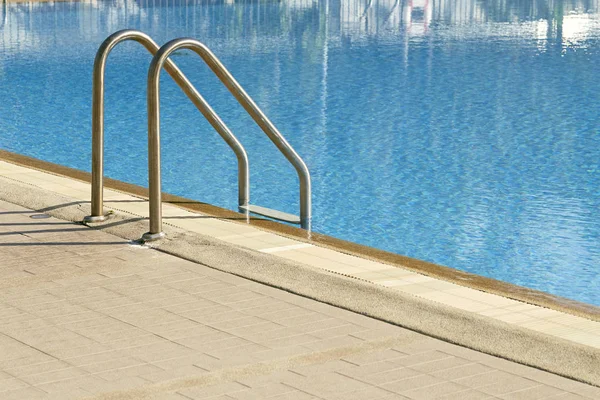 Grab bars ladder in the blue swimming pool