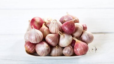 Ahşap beyaz masa arka plan üzerinde seramik kase taze sarımsak