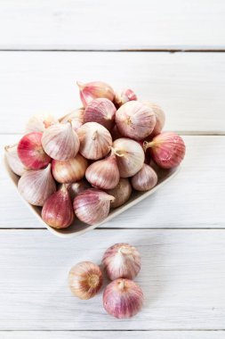 Ahşap beyaz masa arka plan üzerinde seramik kase taze sarımsak