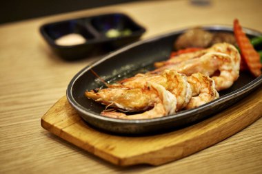 Japon deniz ürünleri. Ahşap şiş üzerinde otlar ile baharatlı karides demir tava, hizmet Fried görünümü kapatın