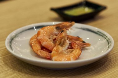 Ahşap masa üzerinde bir tabak içinde pişmiş bütün karides hizmet