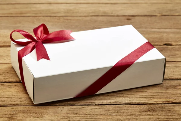 Stock image gift box with red bow on wood table