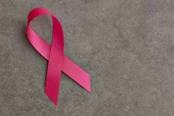 Pink breast cancer ribbon on gray background, minimal concept