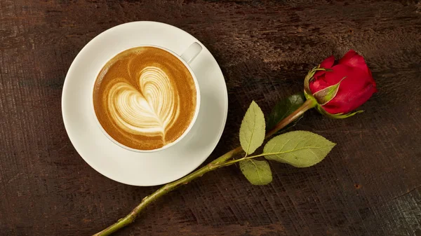 fresh cappuccino with red rose on wood table