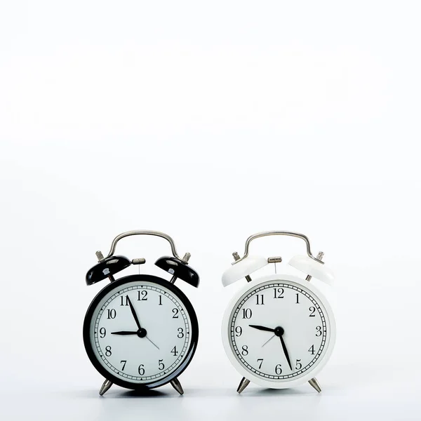 Czarny rocznik budzik i biały zegar na białym — Zdjęcie stockowe