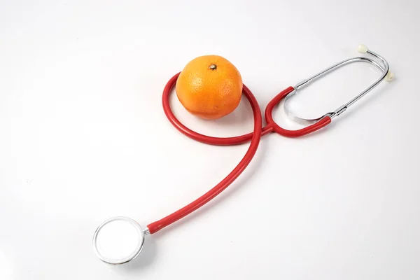 Orangenfrucht mit rotem Stethoskop auf weißem Hintergrund — Stockfoto