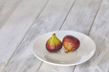 Beyaz ahşap bir tabakta incir