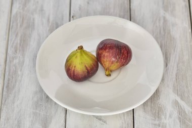 Beyaz ahşap bir tabakta incir