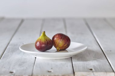 Beyaz ahşap bir tabakta incir