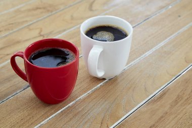 İki kırmızı ve beyaz kupa kahve tahtada