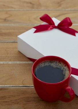 Bir kırmızı kupa kahve ve tahtadan hediye kutusu.