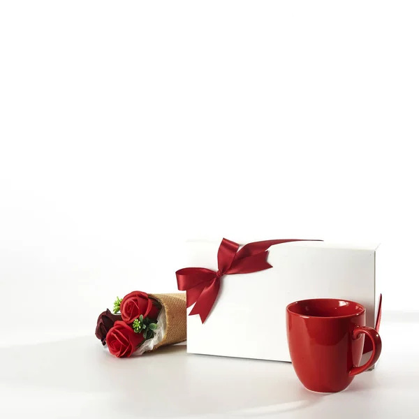 Red cup with gift box and roses on white — Stock Photo, Image