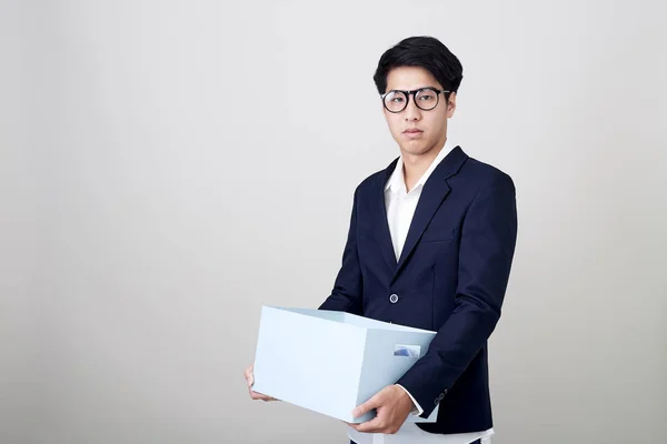 Young asian businessman holding a box — Stock Photo, Image